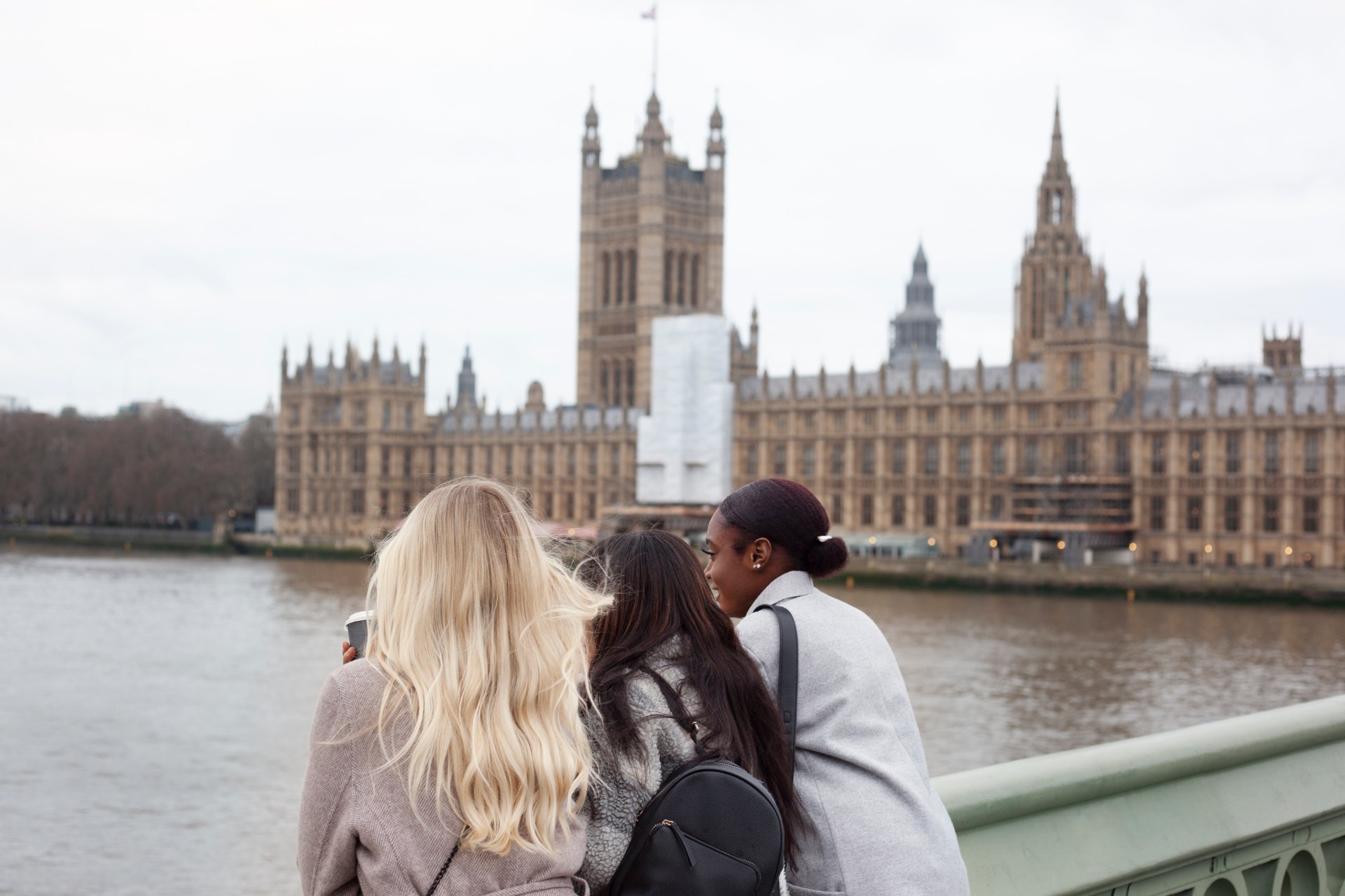Tri mladé ženy pri Temži v Londýne, v pozadí Westminsterský palác